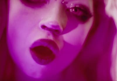 a close up of a woman's face with purple lighting