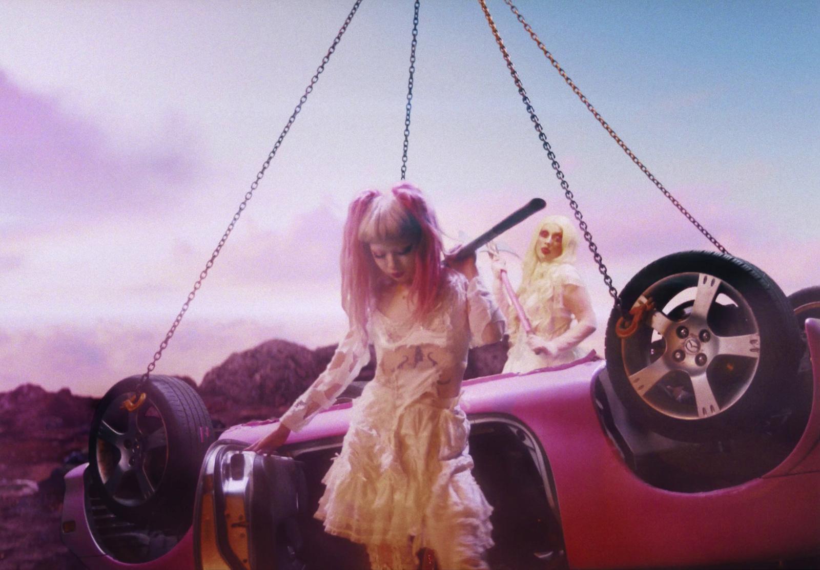 a woman in a dress holding a baseball bat next to a car