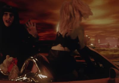 two women in a car with their hands in the air