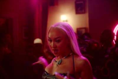 a woman with pink hair is dancing in a dark room