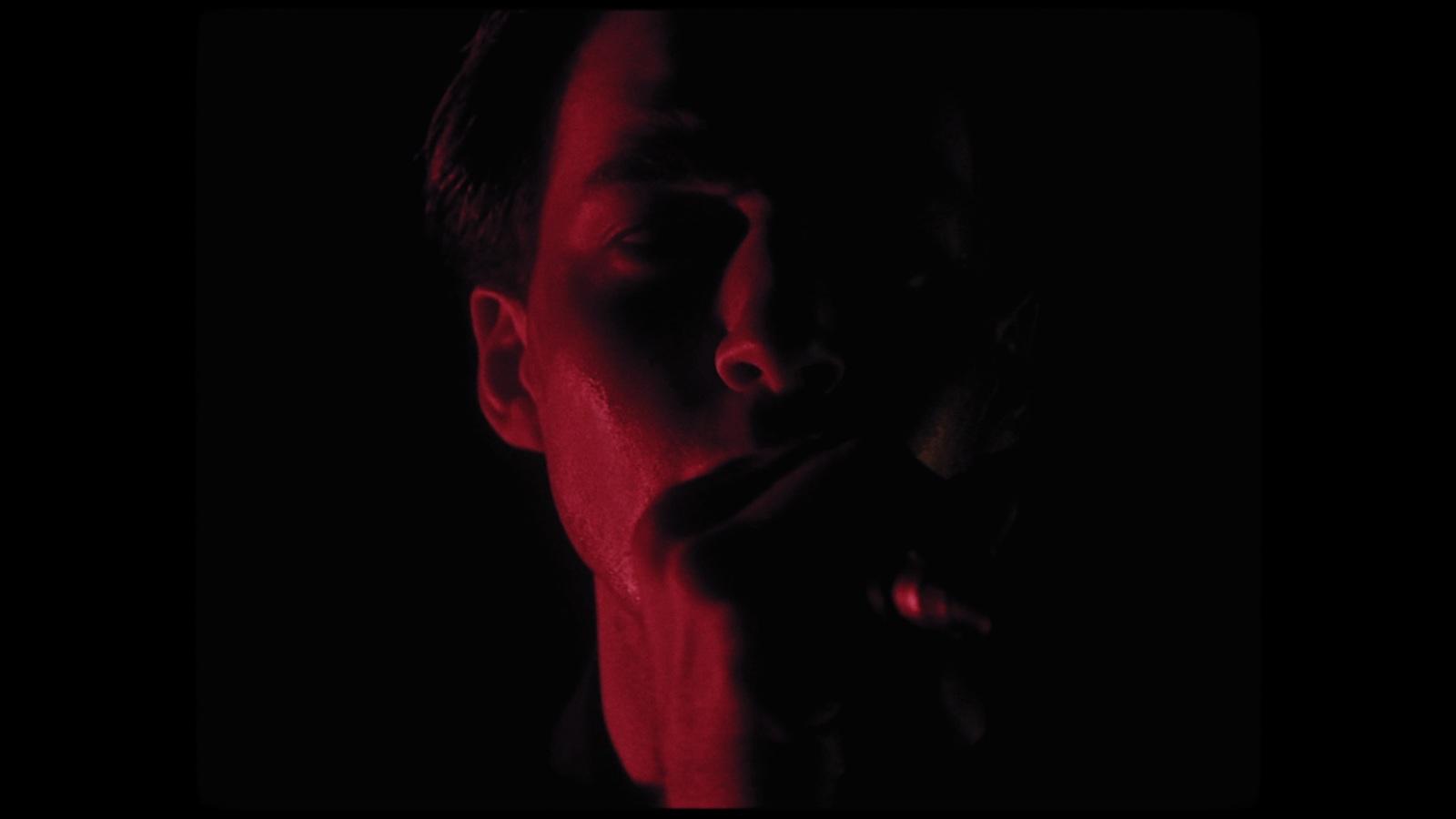 a man with his hand on his mouth in the dark