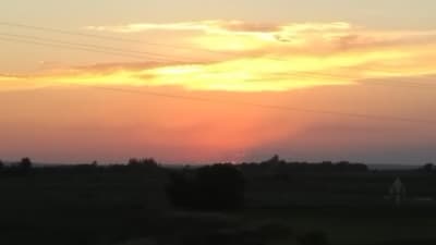 the sun is setting over a field with power lines
