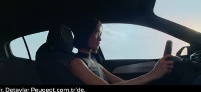 a woman sitting in a car holding a steering wheel