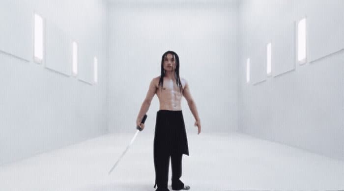 a man with long hair holding a sword in a white room