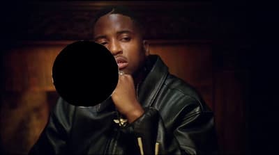a man in a black leather jacket holding his hand to his face