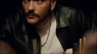 a man in a black leather jacket looking at the camera