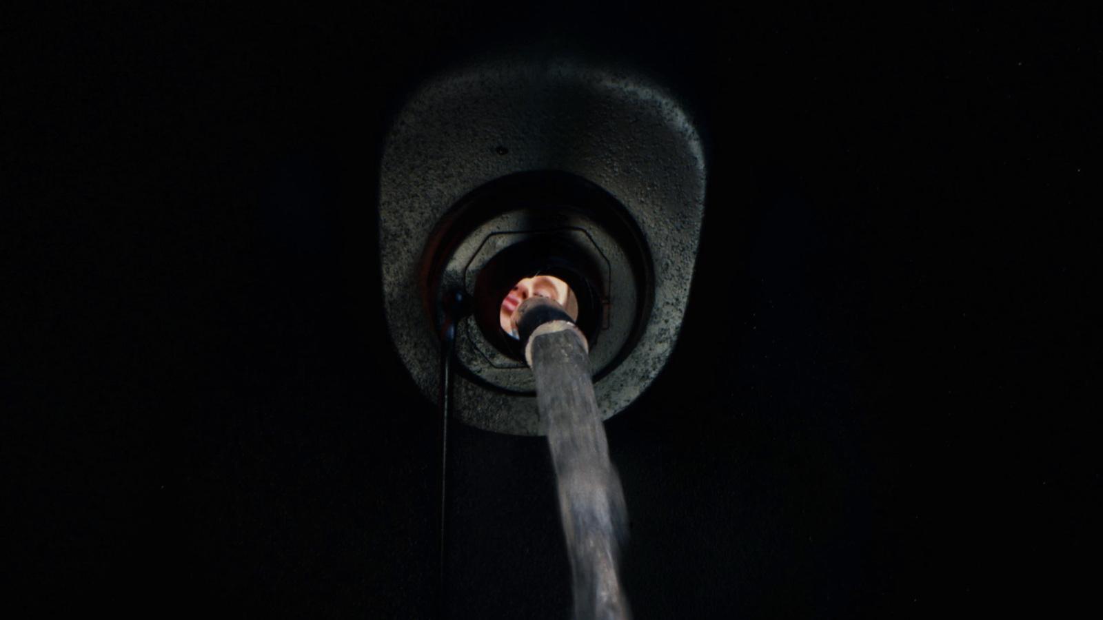 a person in the dark with their hand on a hose