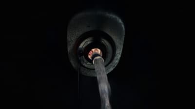 a person in the dark with their hand on a hose
