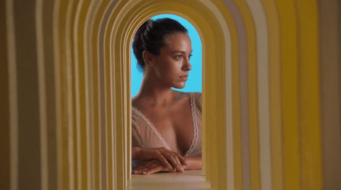 a woman in a white top looking out of a window