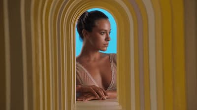 a woman in a white top looking out of a window