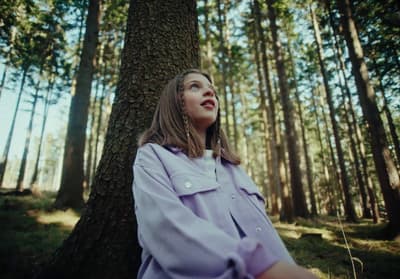 a woman standing in front of a tree in a forest