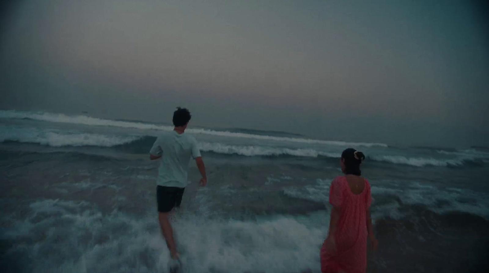 a man and a woman walking into the ocean