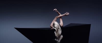 a woman with long blonde hair standing on a black object