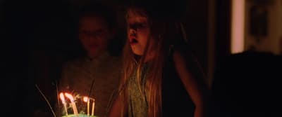 a young girl blowing out candles on a birthday cake