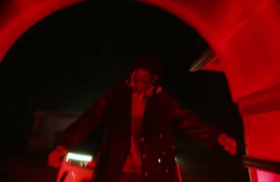a man in a trench coat is walking through a tunnel