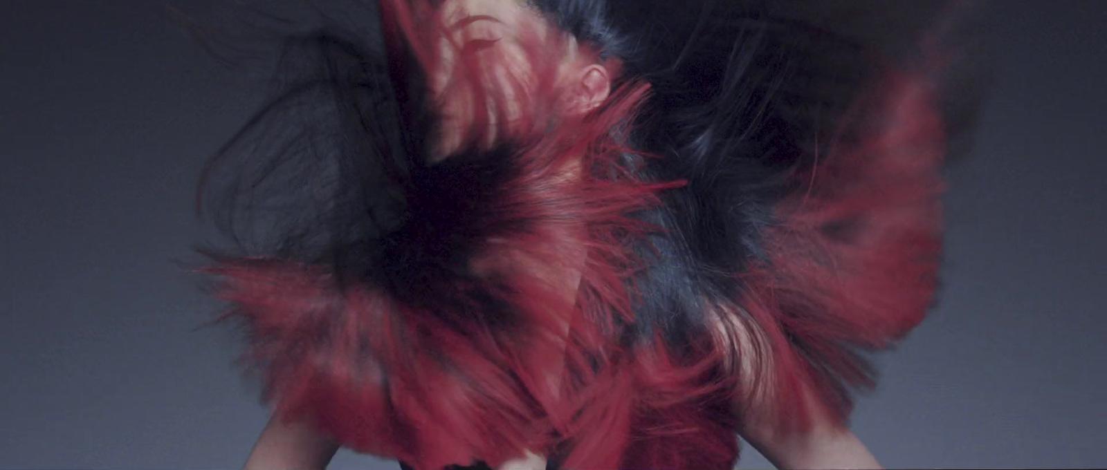 a woman in a red dress with her hair blowing in the wind