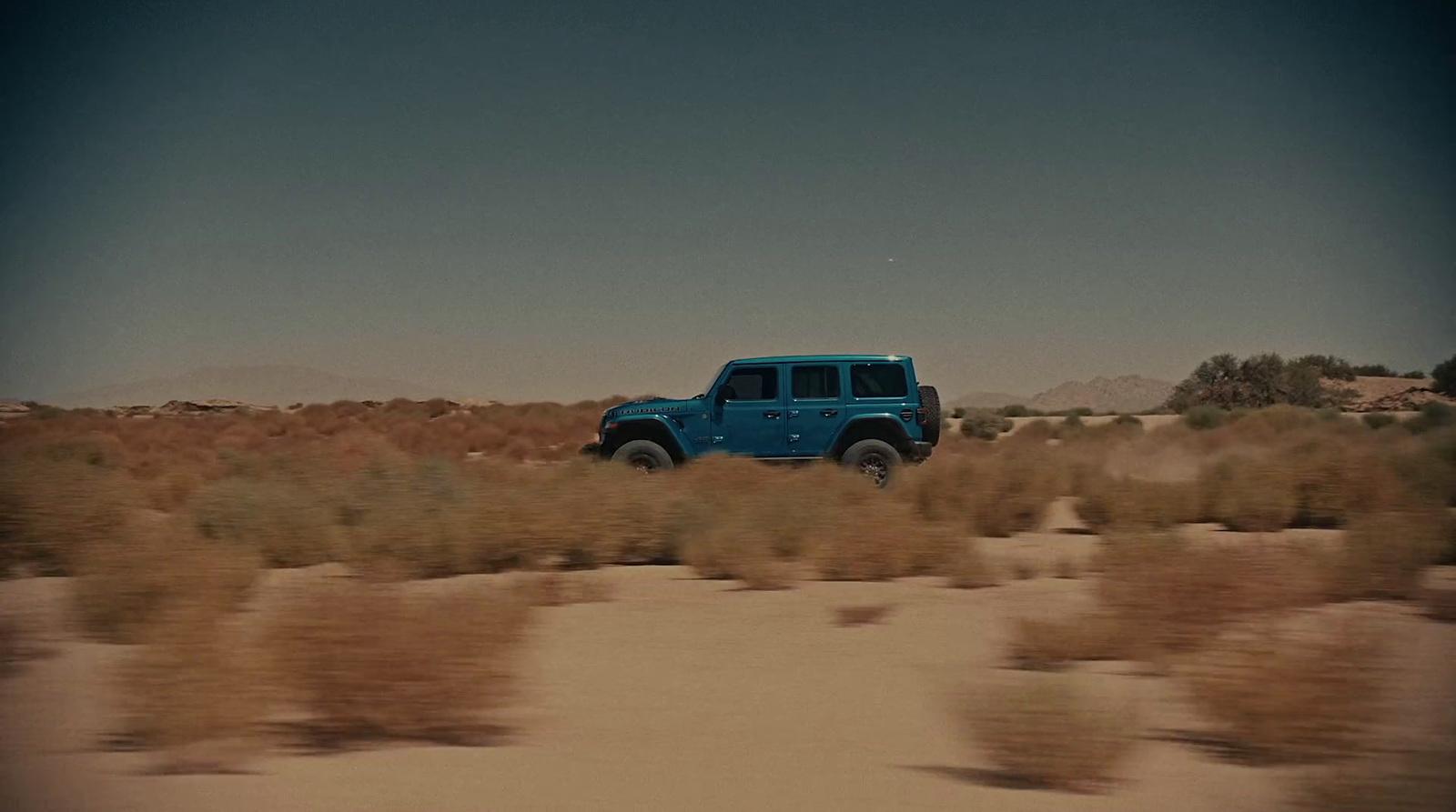 a blue jeep is driving through the desert