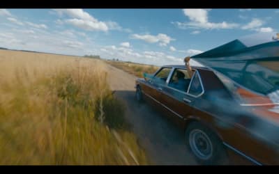 a car driving down a road next to a field