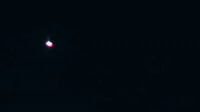 a red light is shining in the dark sky