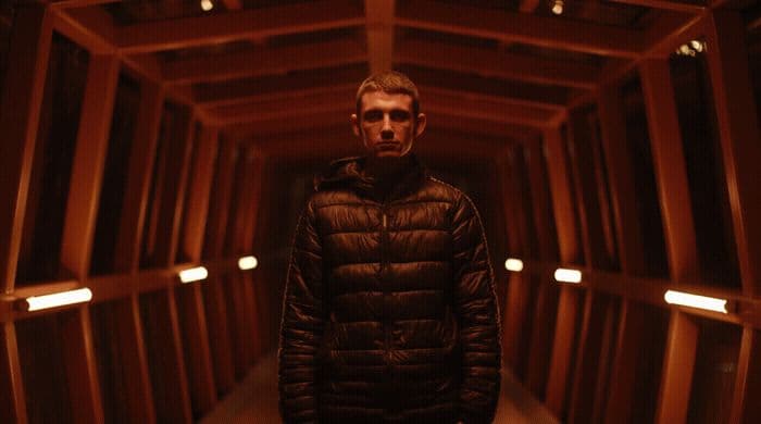a man standing in a dark tunnel with his hands in his pockets