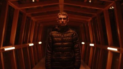 a man standing in a dark tunnel with his hands in his pockets