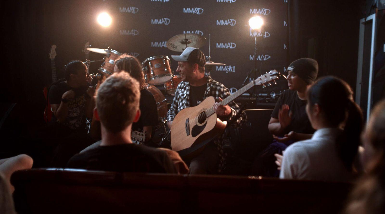 a man playing a guitar in front of a group of people