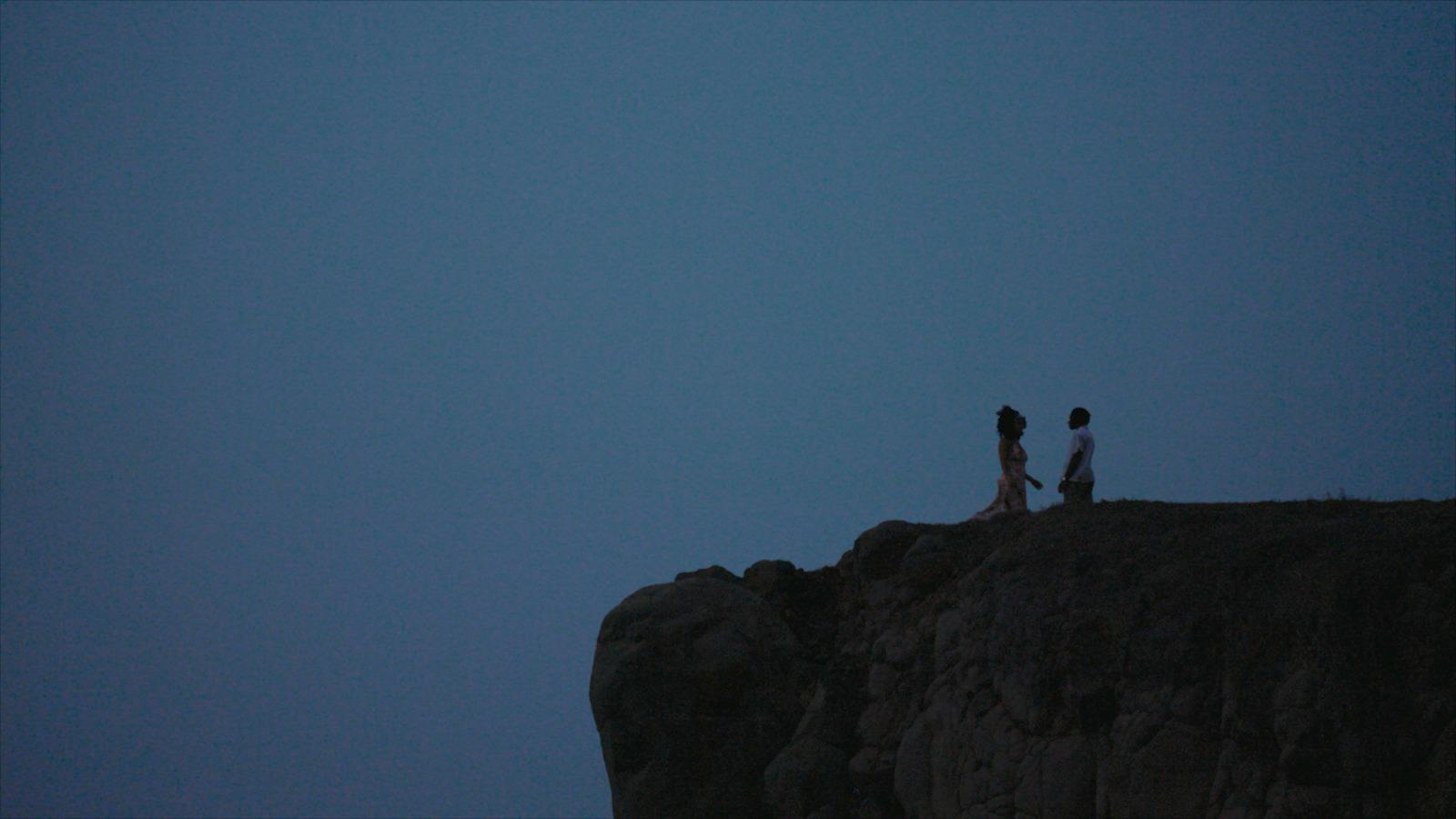 a couple of people standing on top of a cliff