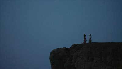 a couple of people standing on top of a cliff