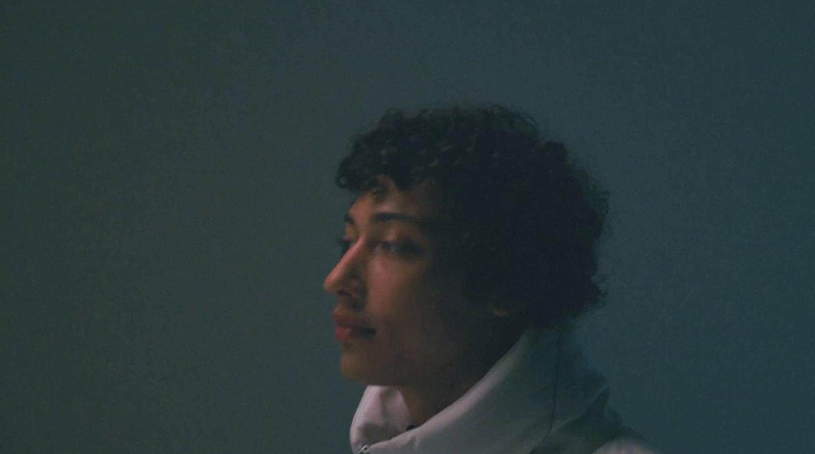 a woman with curly hair wearing a white coat