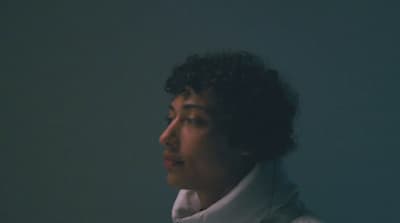 a woman with curly hair wearing a white coat