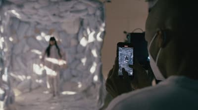 a man taking a picture of a woman in a white room
