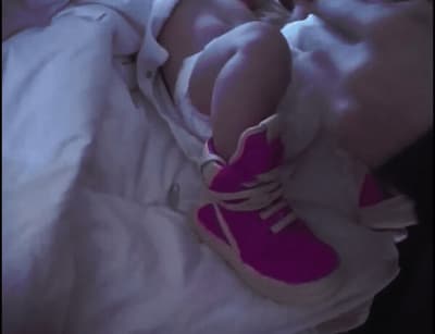 a person laying in a bed with a pink shoe
