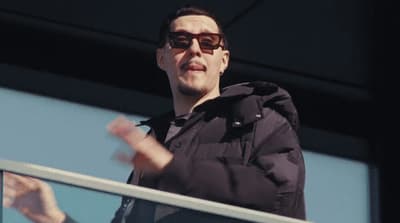 a man wearing sunglasses standing on a balcony