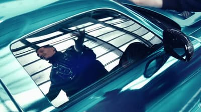 a man in a blue shirt is standing in a blue car