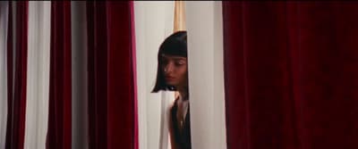 a woman peeking out from behind a curtain