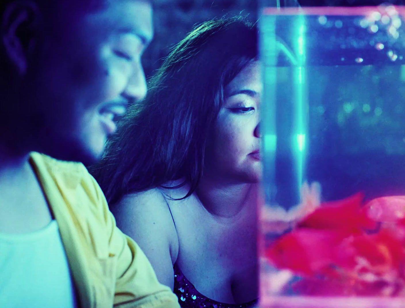 a man and a woman looking at a fish in a tank
