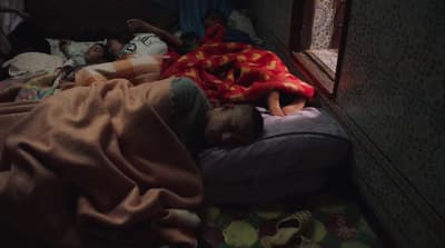a person sleeping on a bed with a red blanket