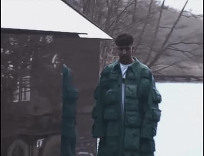 a man in a green jacket standing in front of a building