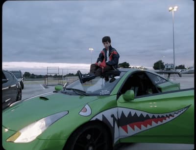 a man sitting on top of a green sports car