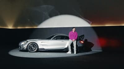 a man standing next to a car on a stage
