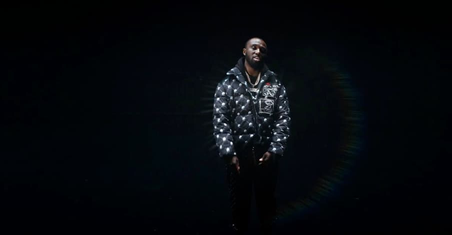 a man standing in the dark with his hands in his pockets