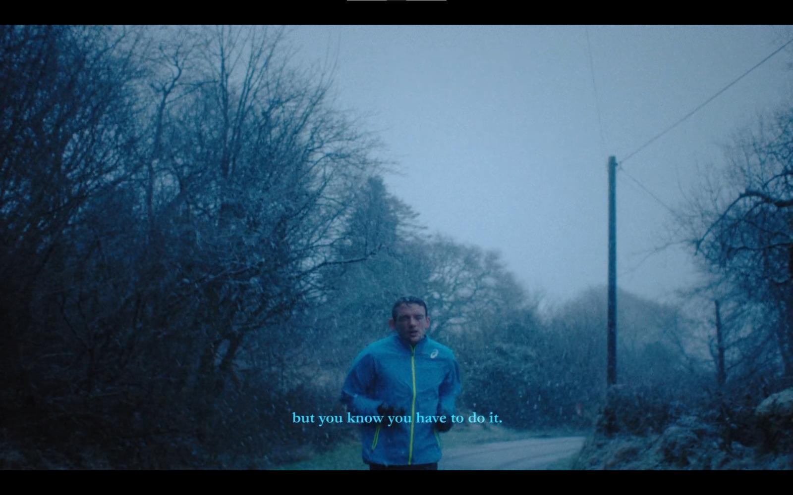 a man in a blue jacket is running in the snow