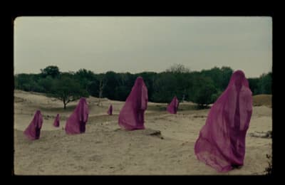 a group of purple cloths sitting on top of a sandy beach
