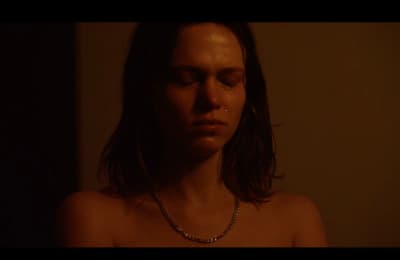 a woman wearing a necklace in a dark room