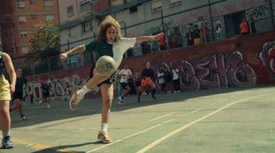 a girl kicking a soccer ball on a court