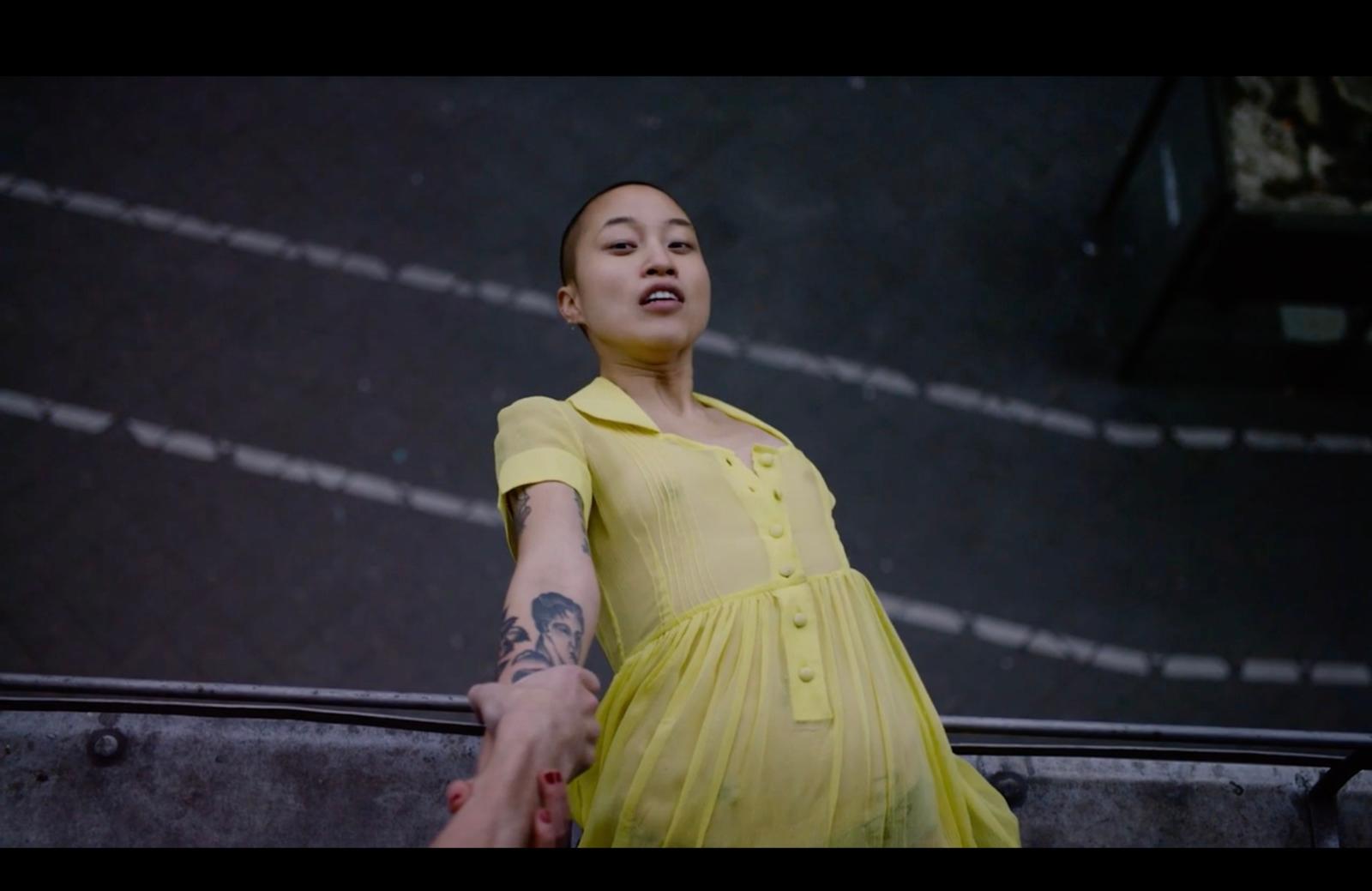 a woman in a yellow dress holding the hand of a man
