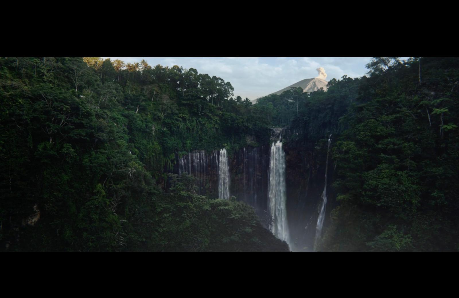 a large waterfall surrounded by lush green trees