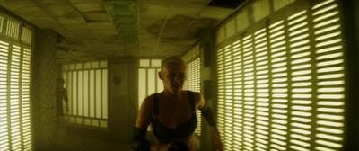 a woman standing in a hallway with blinds on the walls