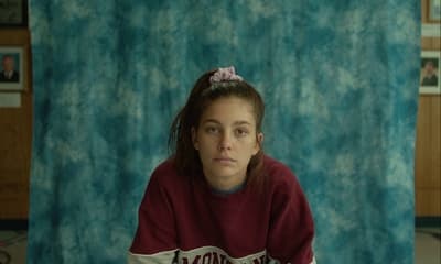 a woman sitting in front of a blue curtain