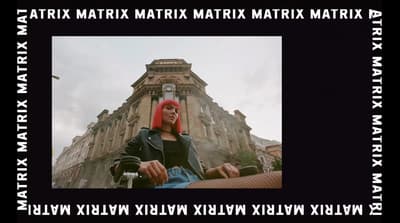 a woman with red hair sitting in front of a building